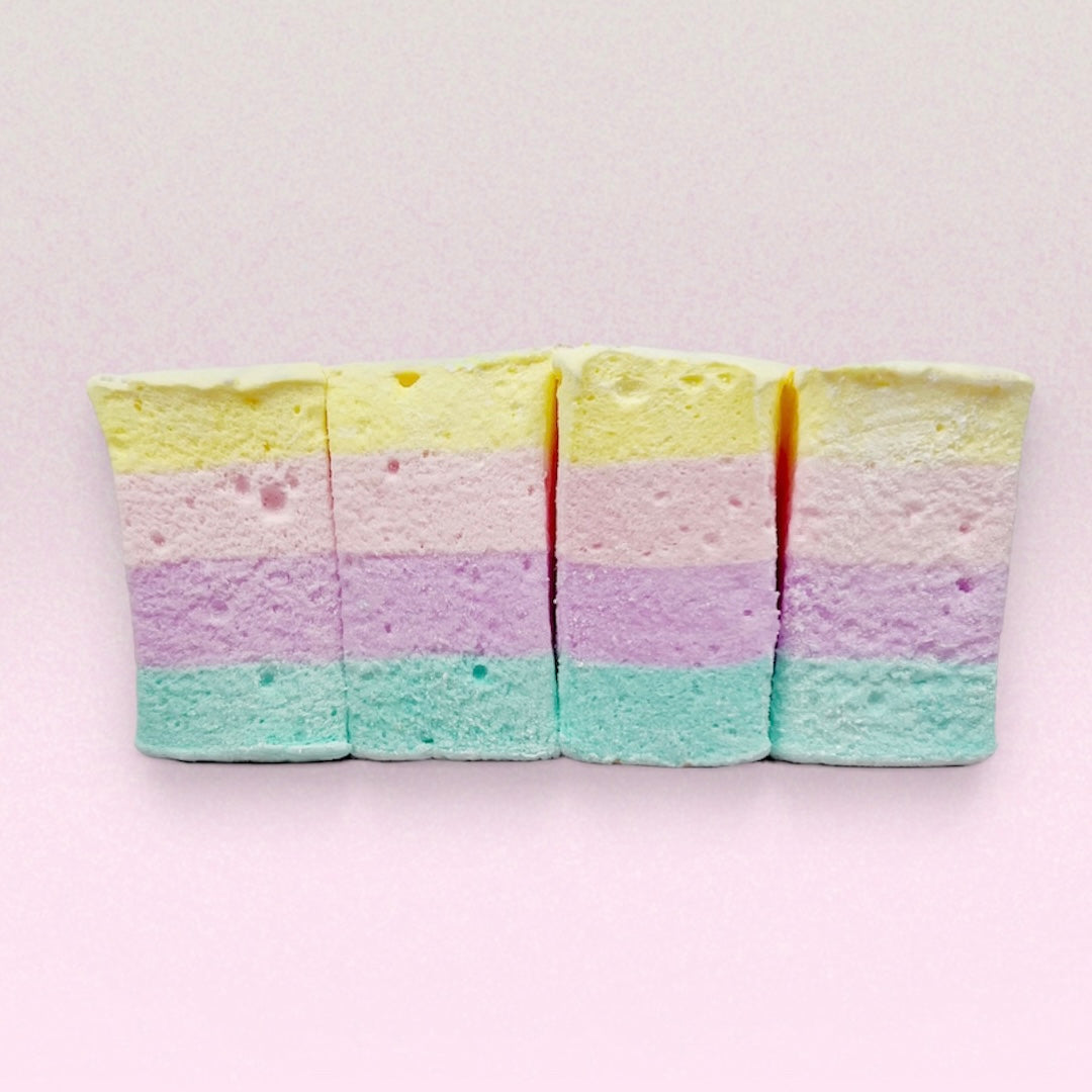 Five layered marshmallows with pastel colors on a light pink background