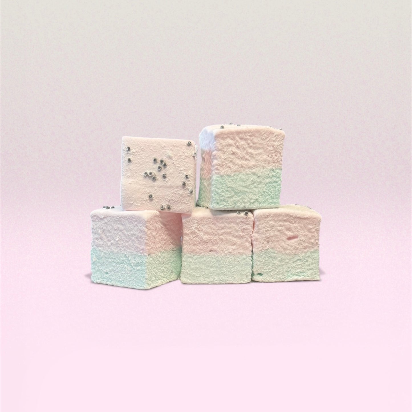 Stack of pastel-colored marshmallows on a light pink background