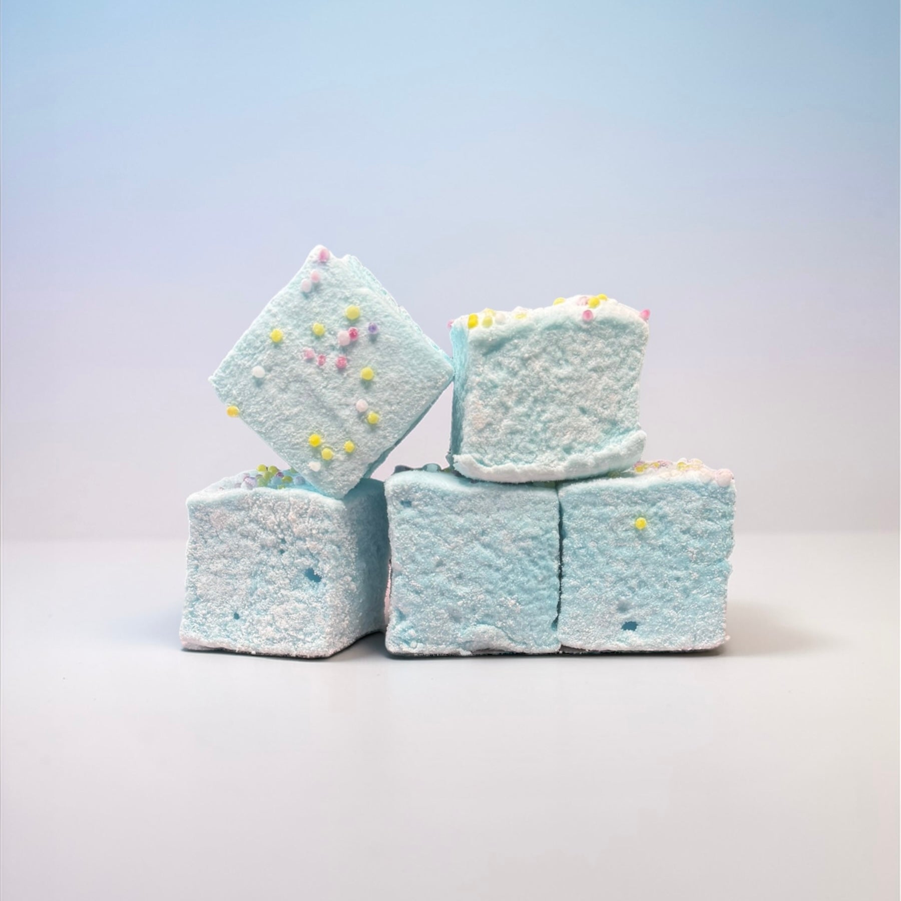 Stack of light blue marshmallows with colorful sprinkles on a white background