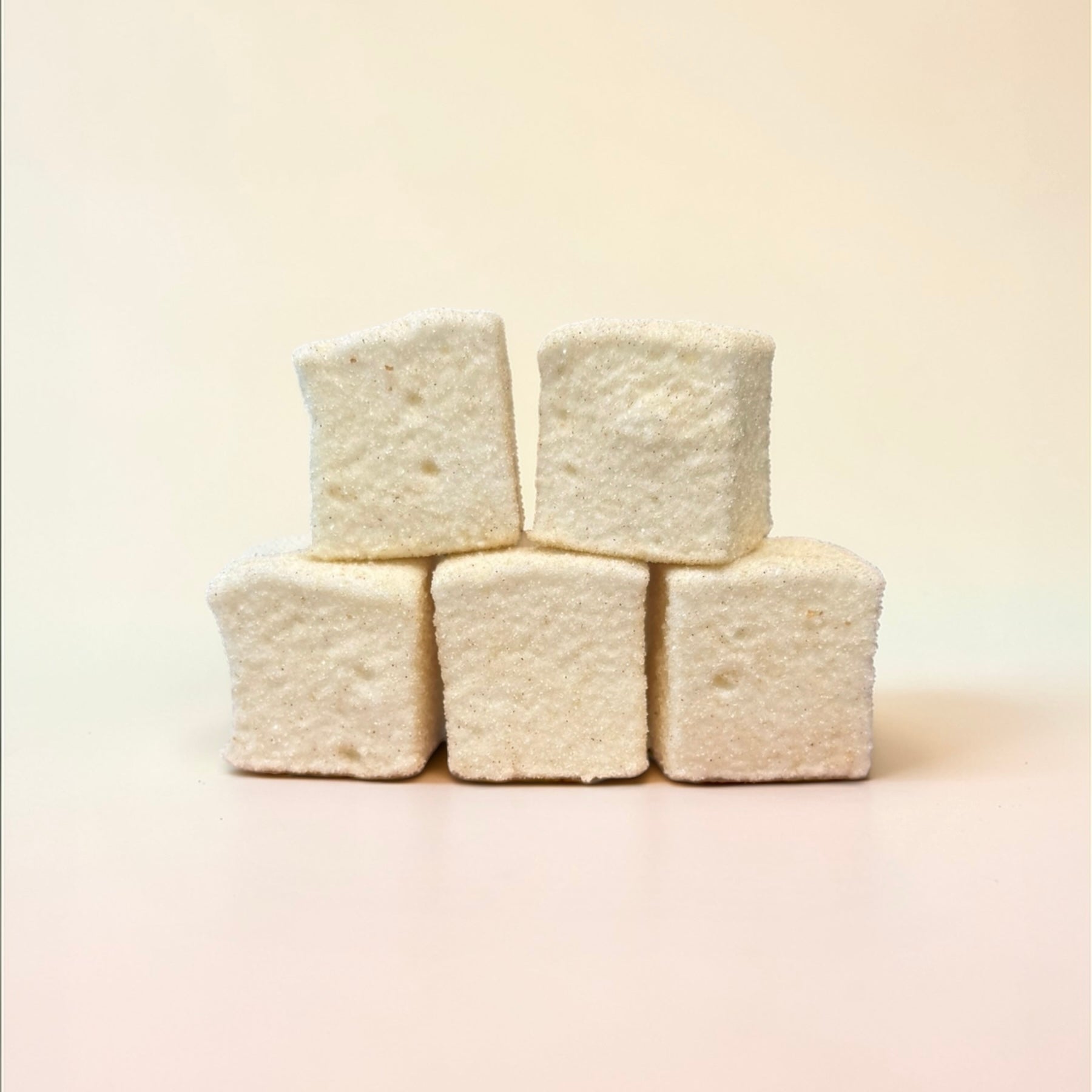 Stack of white marshmallows on a beige background