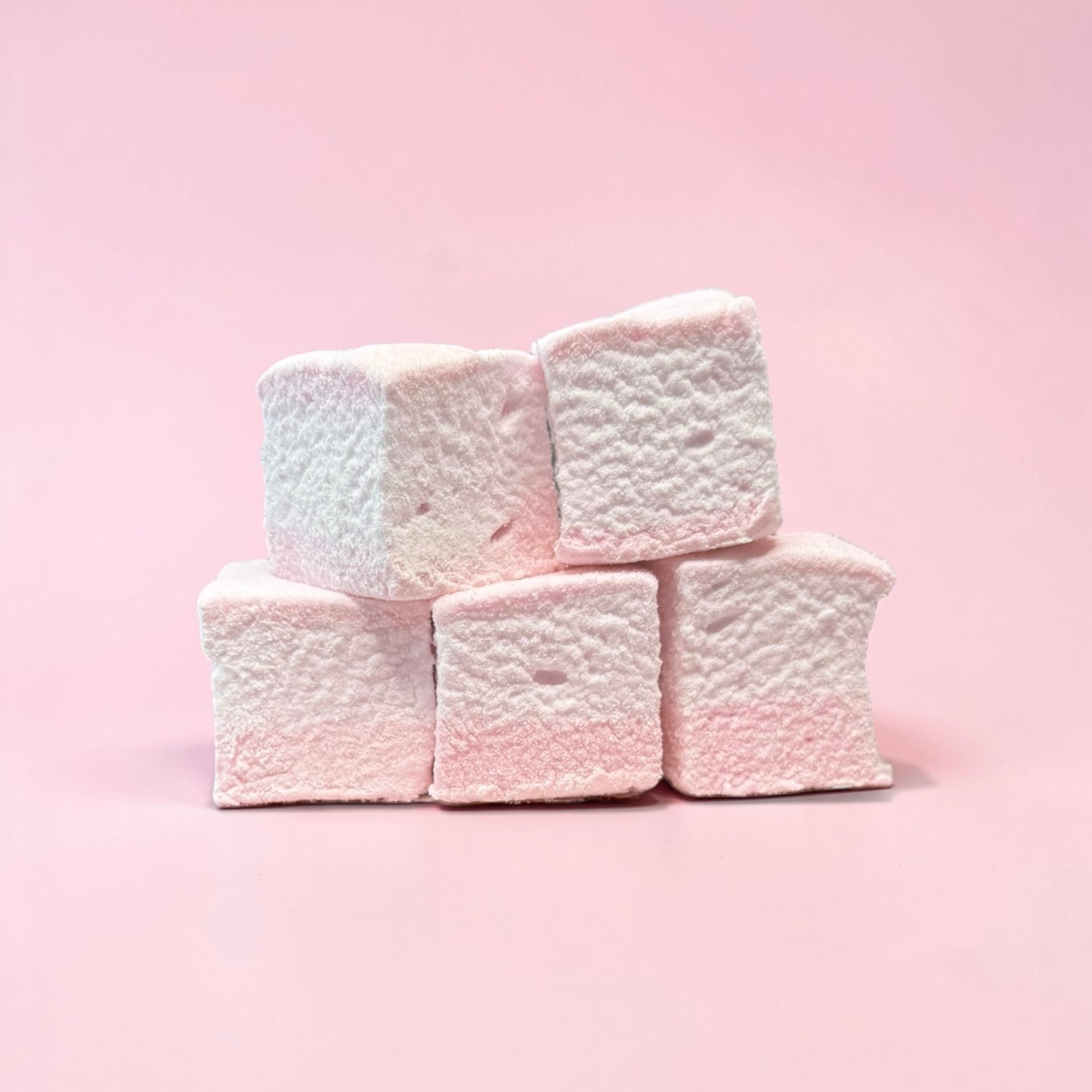 Stack of pink marshmallows on a pink background