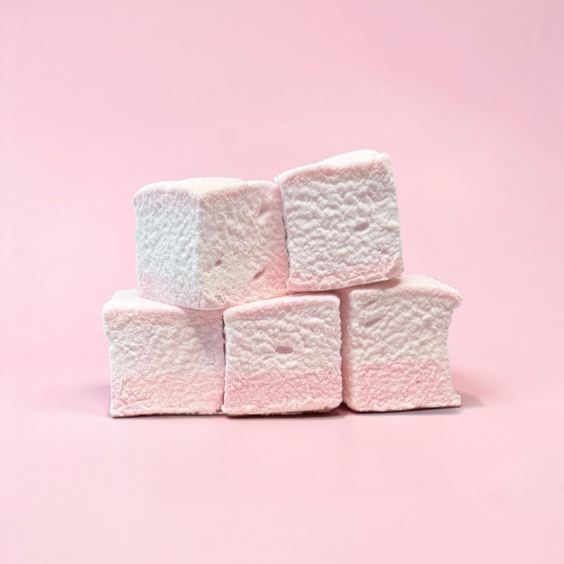 Stack of pink marshmallows on a pink background