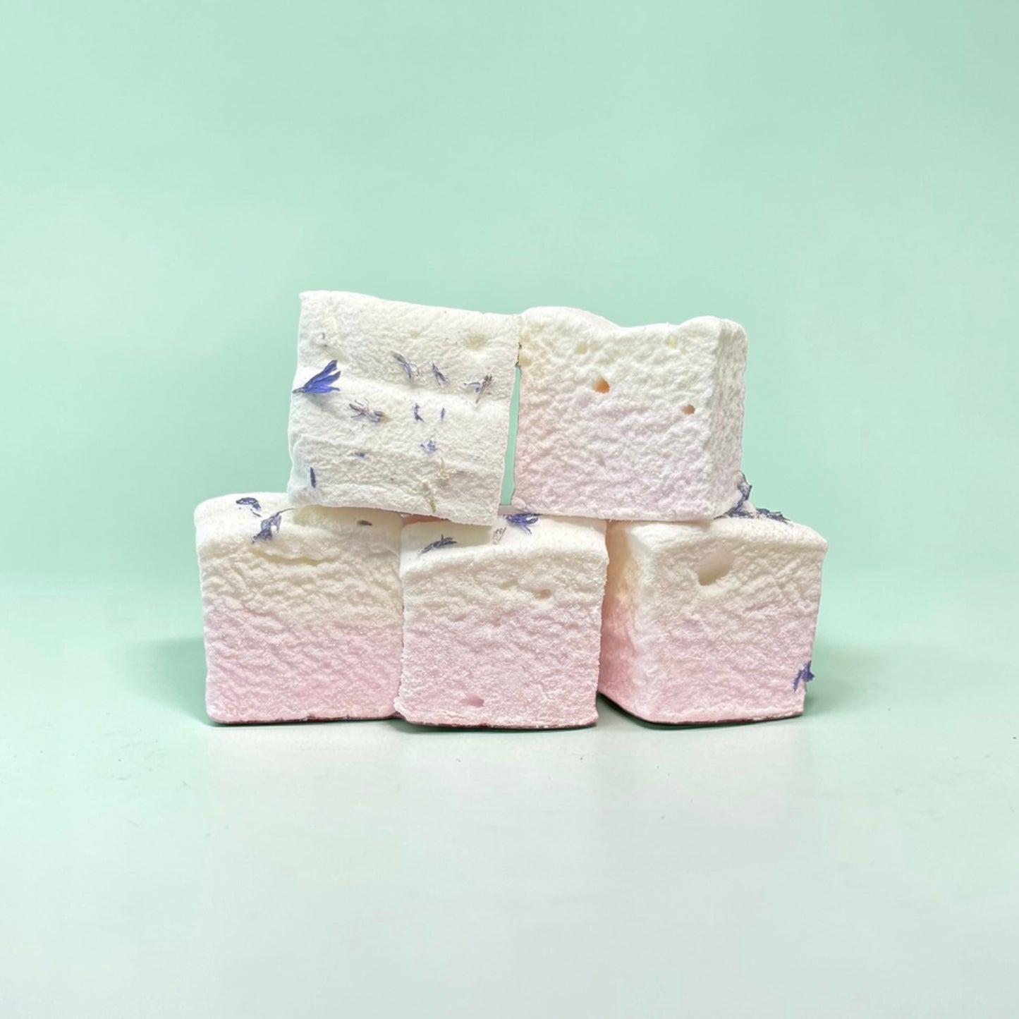 Stack of white marshmallows with blue and purple decorations on a light green background