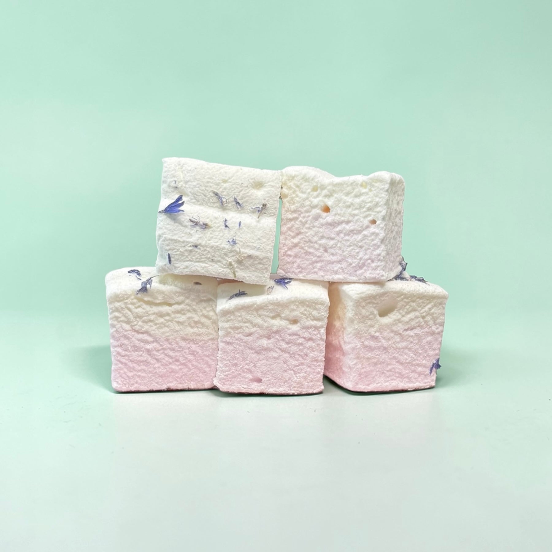 Stack of white marshmallows with blue and purple decorations on a light green background