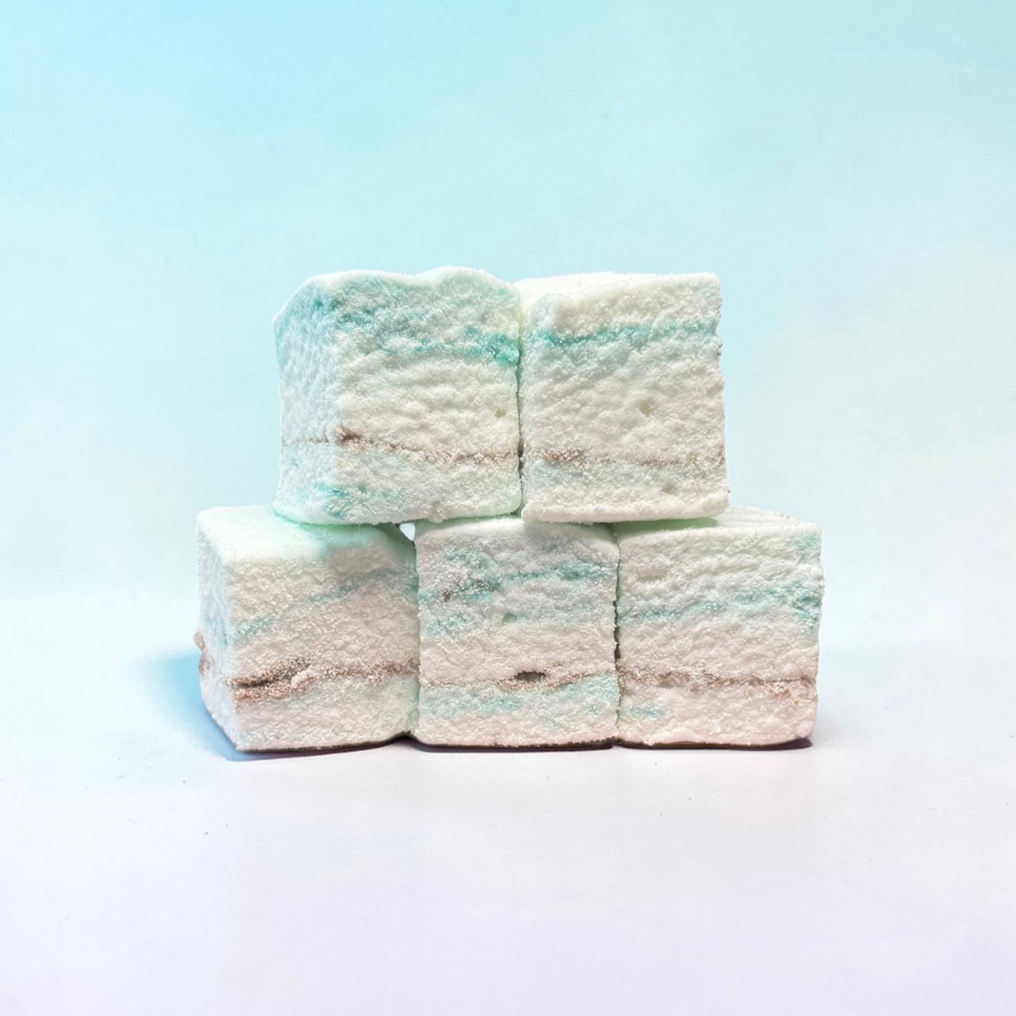 Stack of white and blue marshmallows on a light blue background