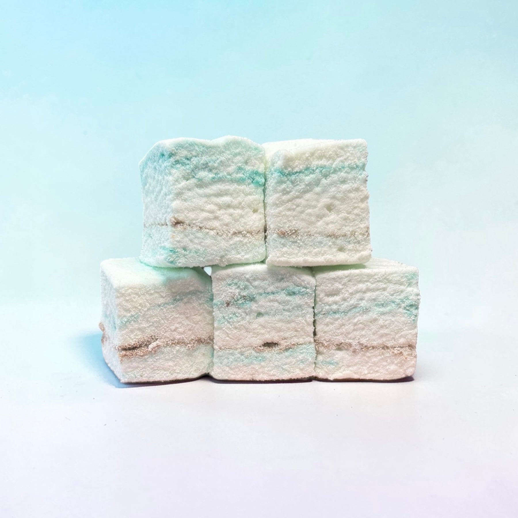 Stack of white and blue marshmallows on a light blue background