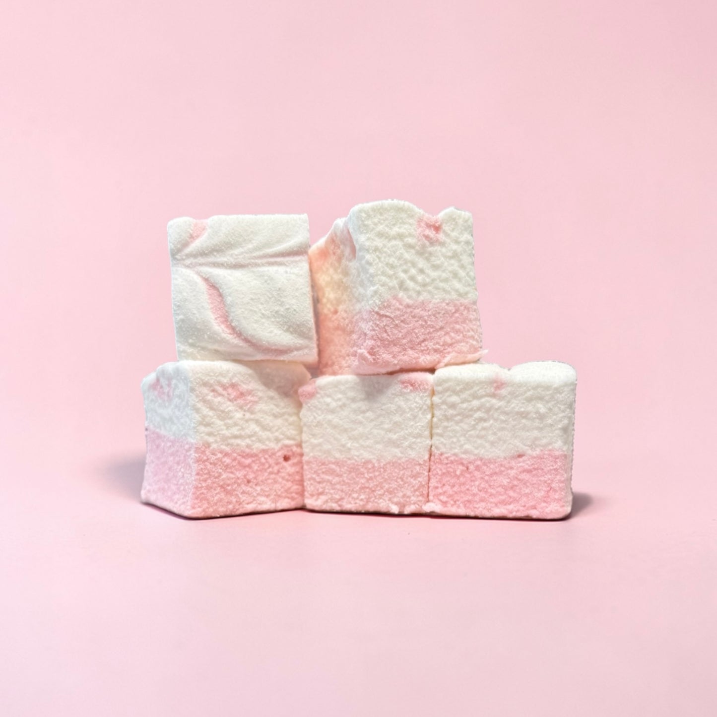 Stack of pink and white marshmallows on a pink background