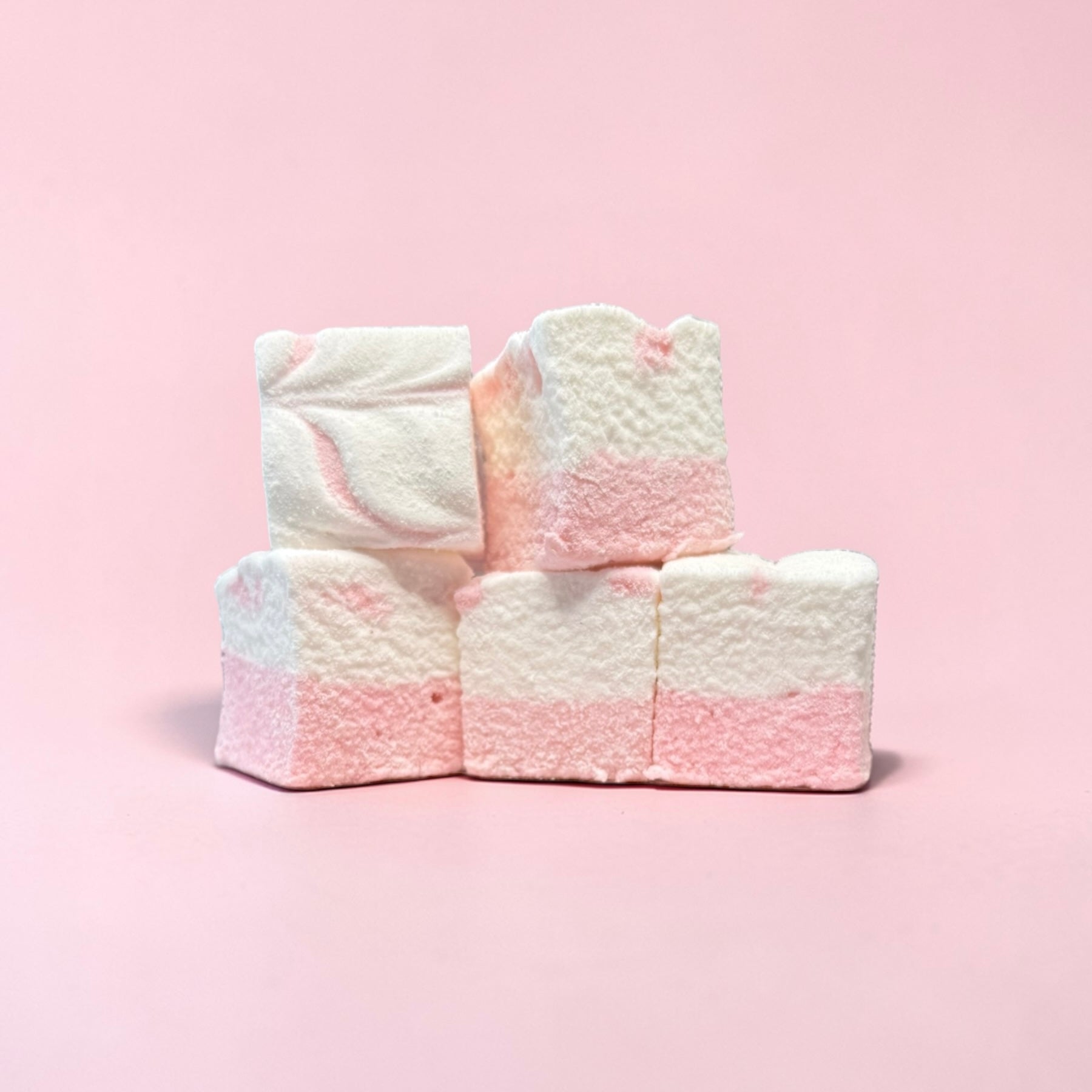 Stack of pink and white marshmallows on a pink background