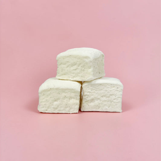 Three white marshmallows stacked on a pink background