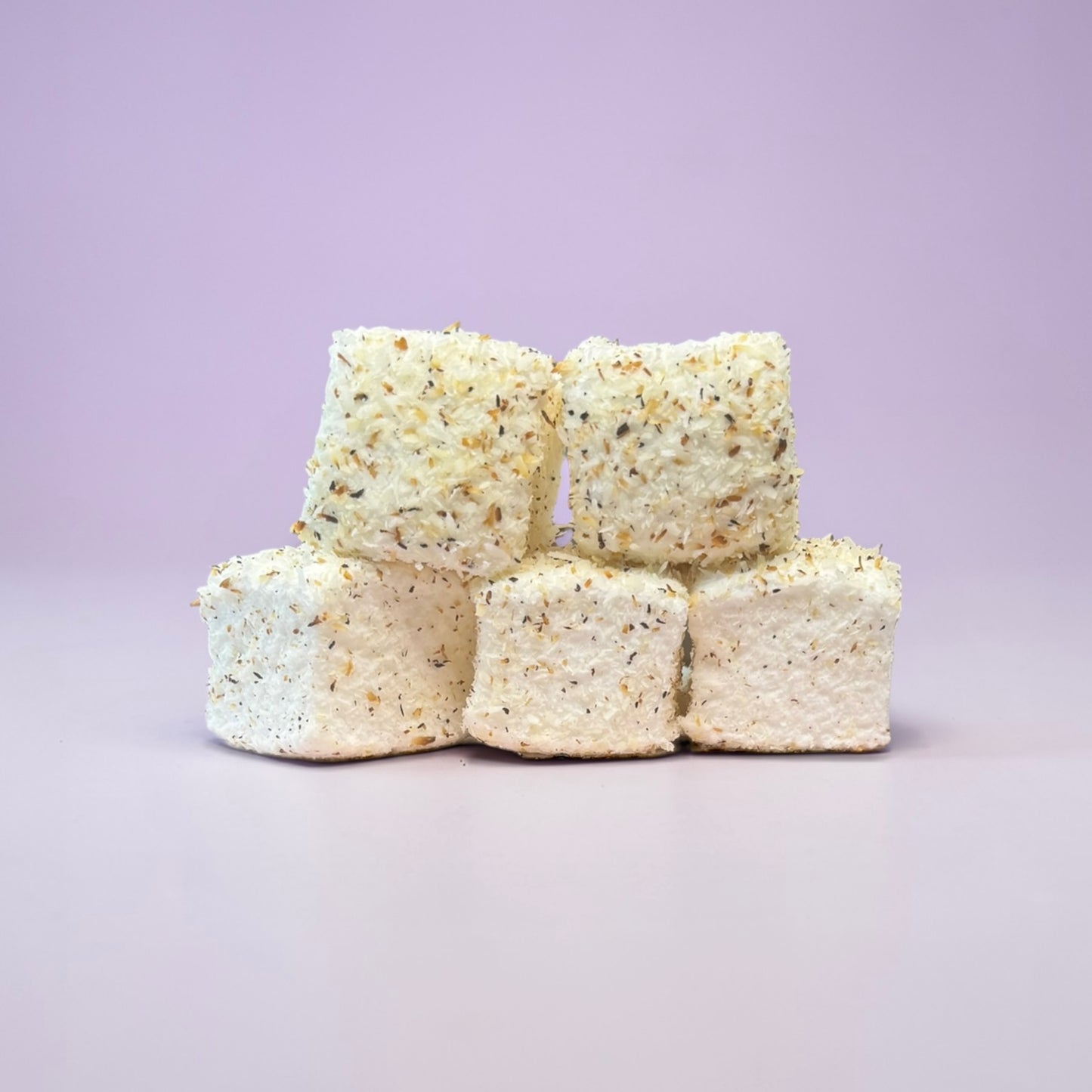 Five square-shaped marshmallows stacked on a light purple background