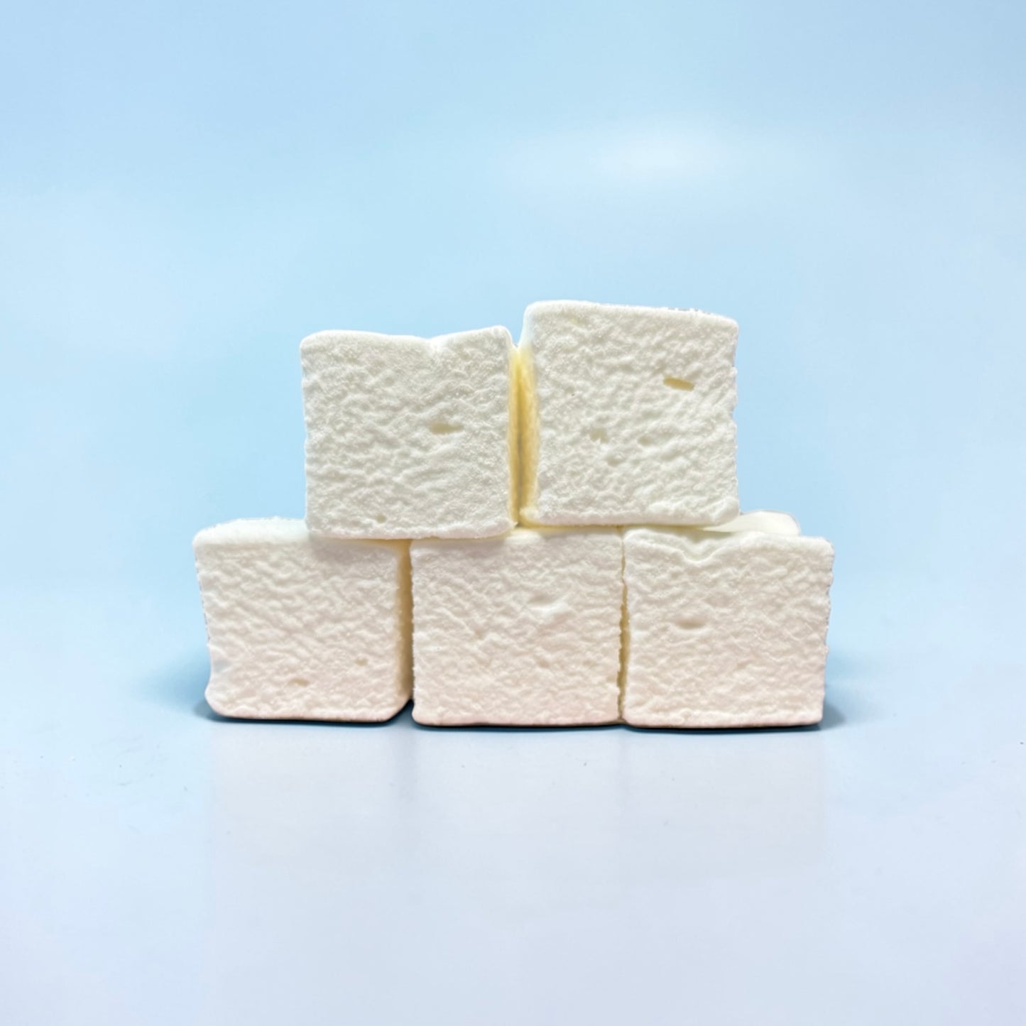 Stack of white marshmallows on a light blue background