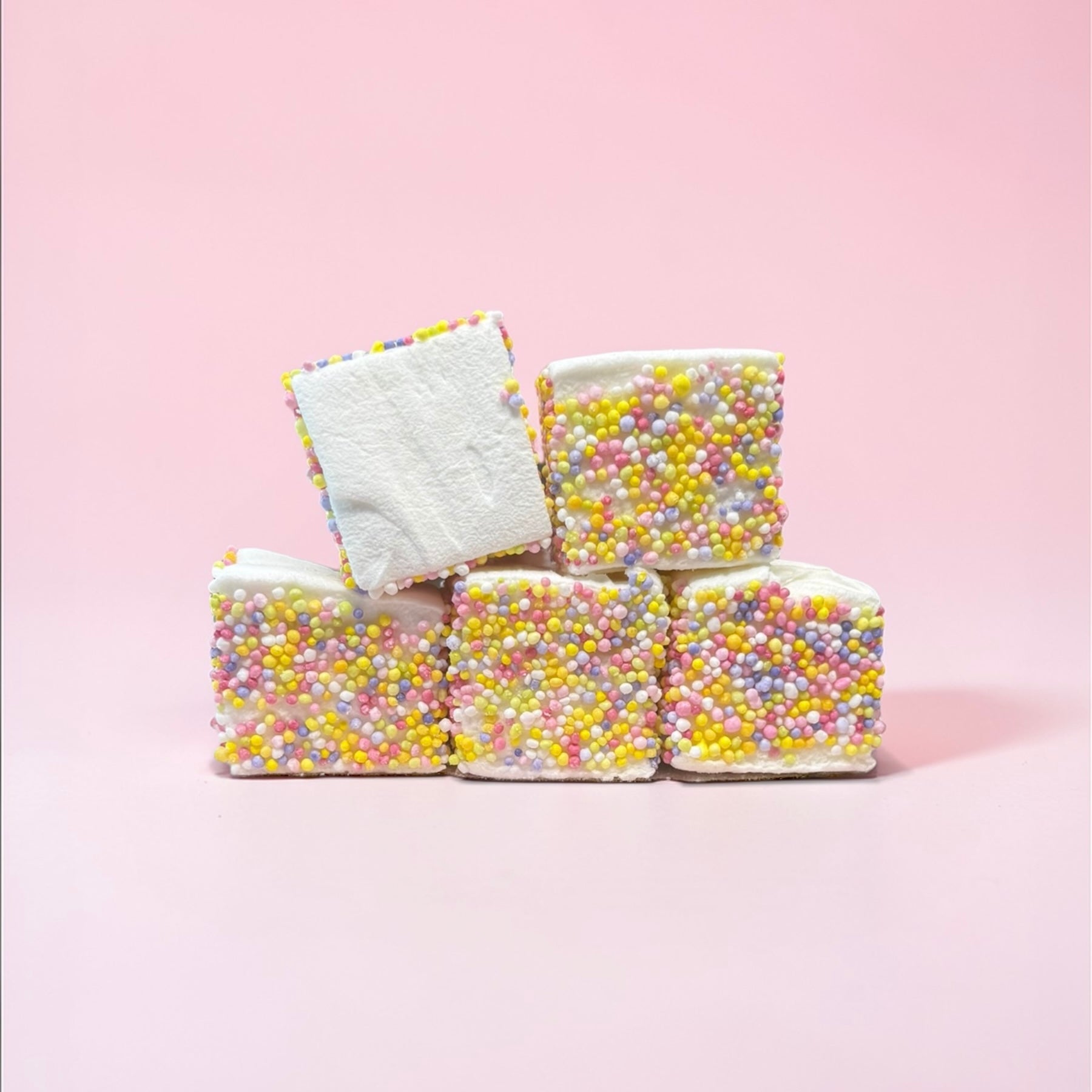 Marshmallows with colorful sprinkles on a pink background